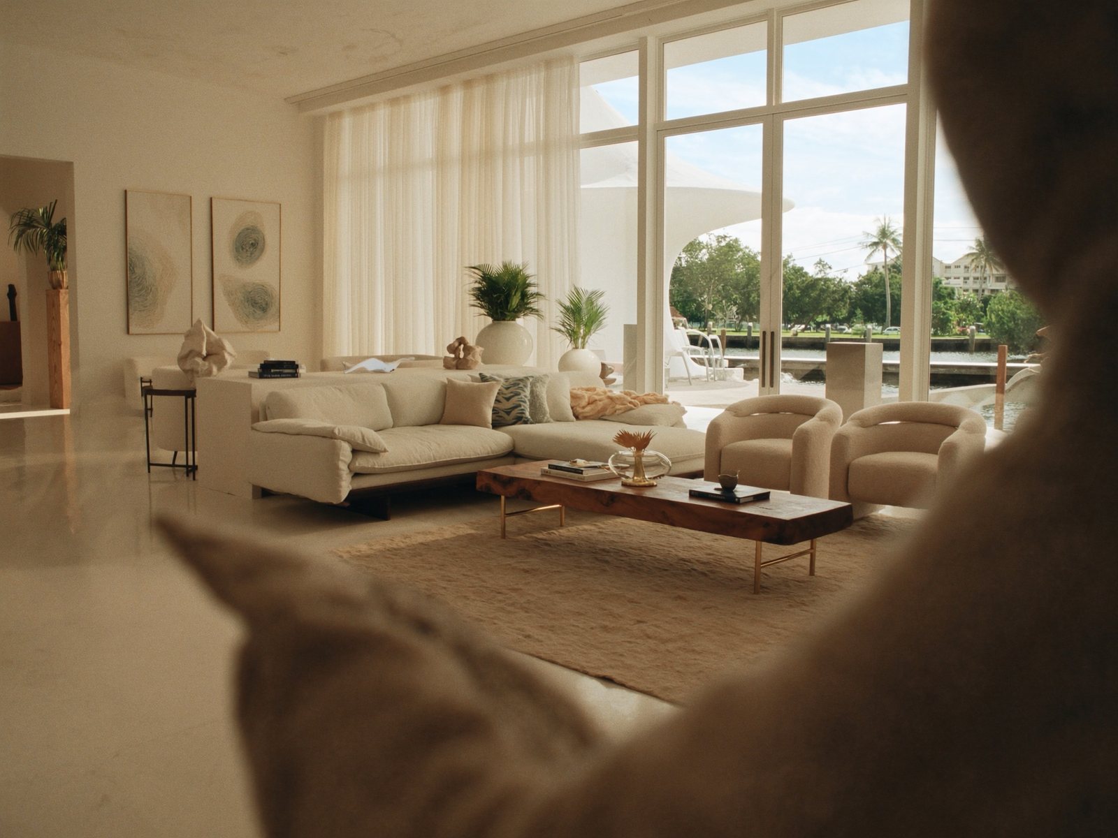 Luxury Fort Lauderdale waterfront living room with ivory linen sectional, boucle accent chairs, and canal views through open glass doors