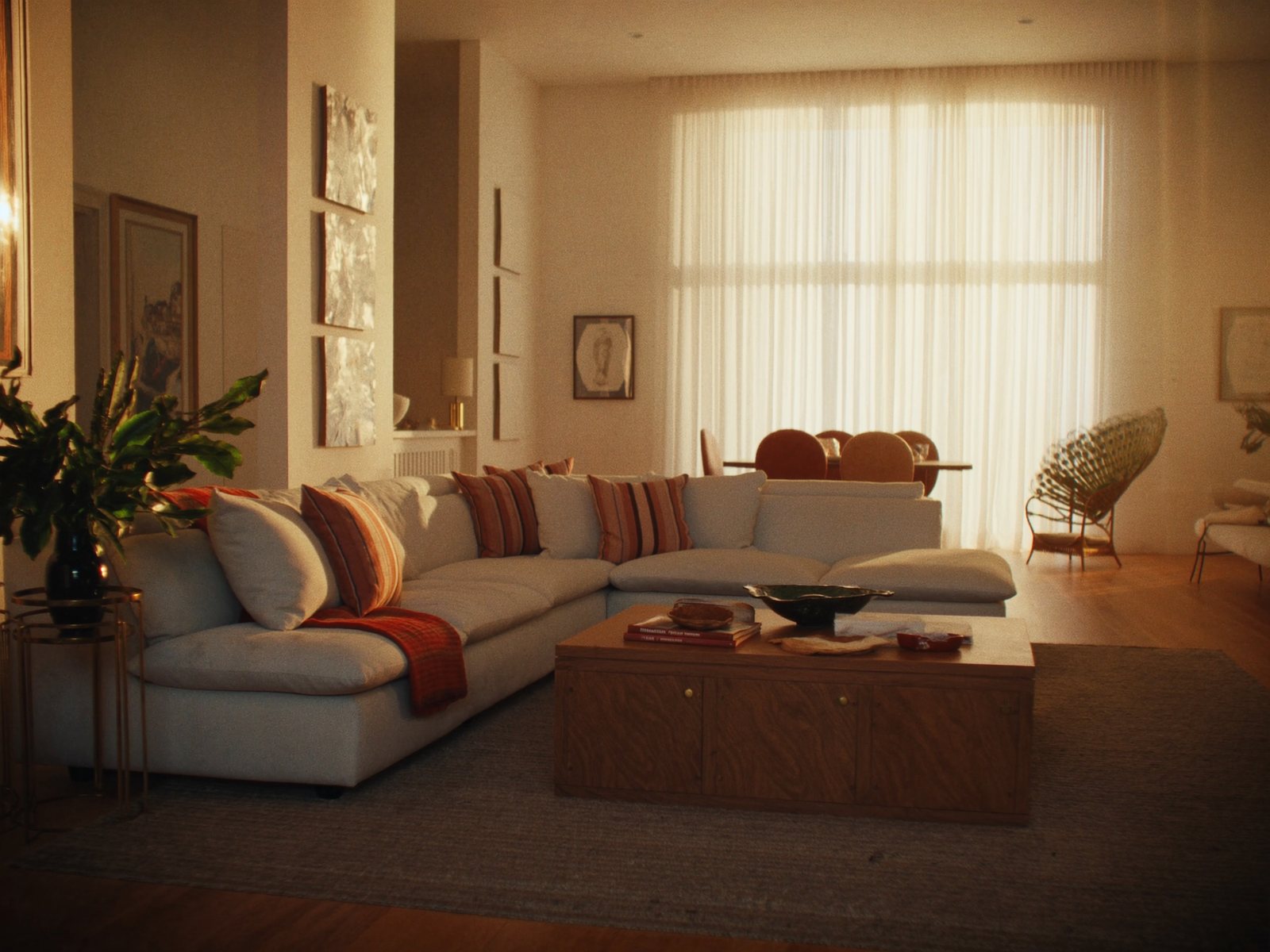 Warm, spacious South Florida family living room with a plush gray sectional, wood coffee table, and tropical plants in natural afternoon light