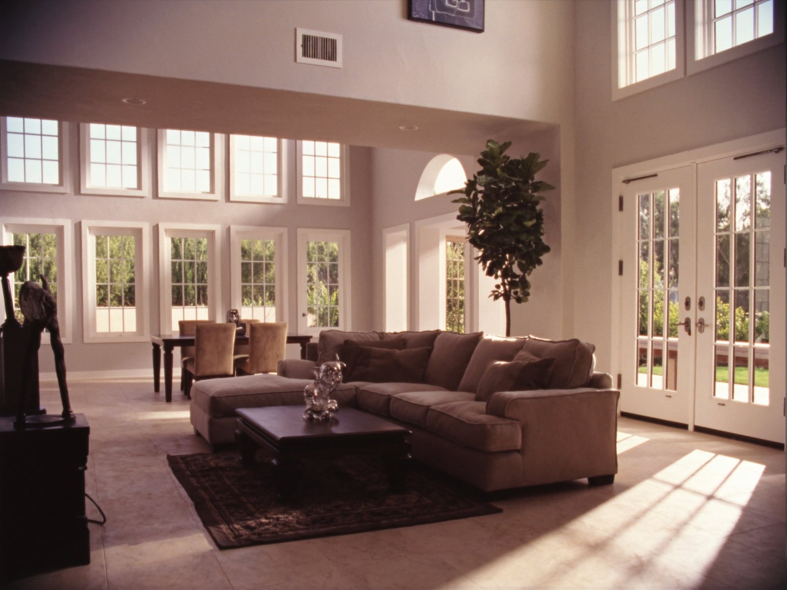 Sun-filled family living room in a new Lakeland, Florida home with a neutral sectional, wood coffee table, and open-plan dining area visible in the background
