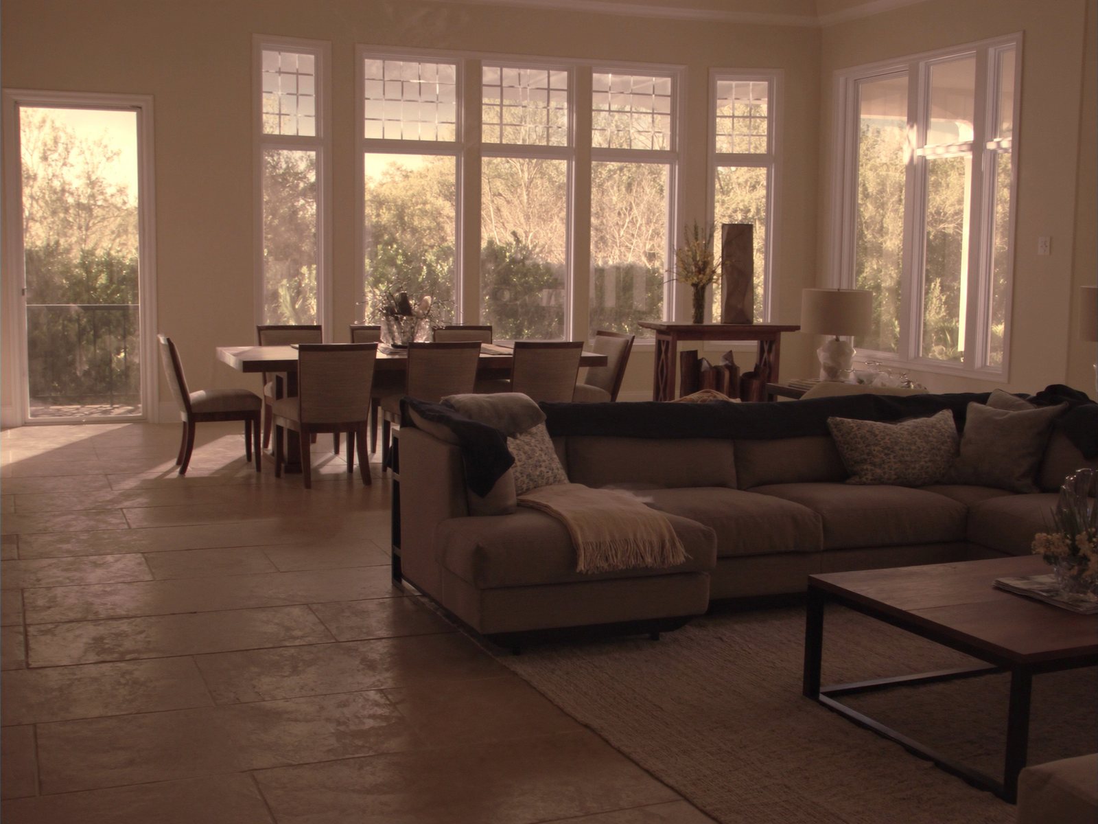 Sunlit open-plan living and dining room in a Pembroke Pines family home, featuring a charcoal sectional, wood coffee table, and six-seat dining set with natural Florida light